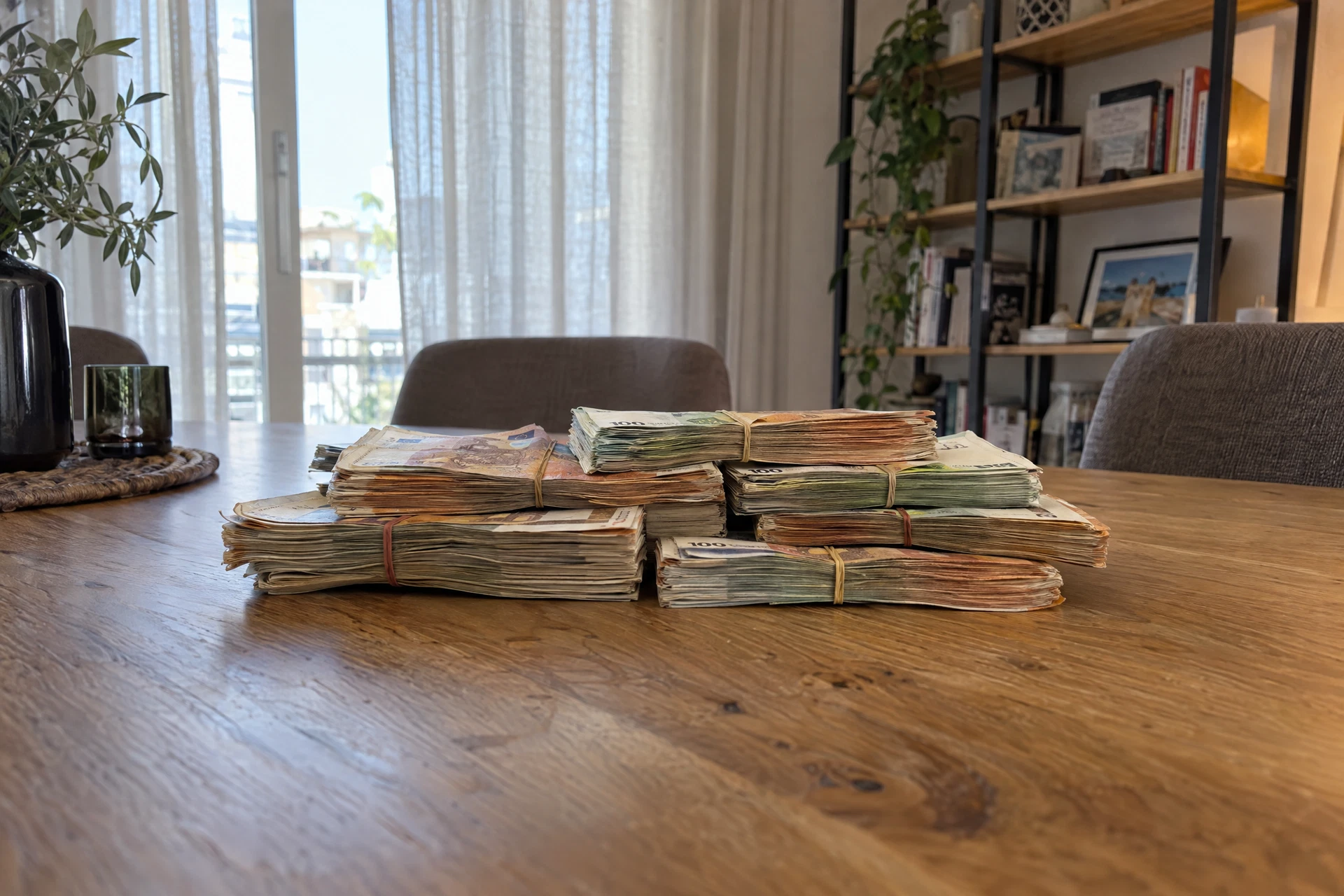 Illustrative scene of euros bundles held with rubber bands viewed edge-on from farther back on a dining table at home